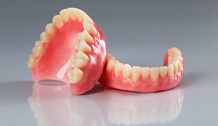 Complete set of dentures on reflective gray surface