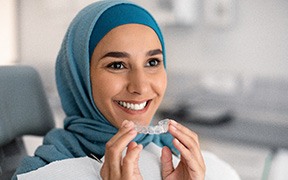 Woman with blue headwrap in dental chair removing her Invisalign