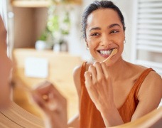 Woman smiling while brushing her teeth