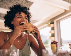 Man smiling while eating sandwich in restaurant