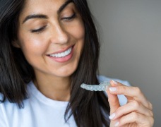 Smiling woman holding clear aligner