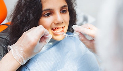 Dentist placing clear aligner on teenager