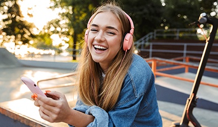 Teen girl smiling while listening to music outside