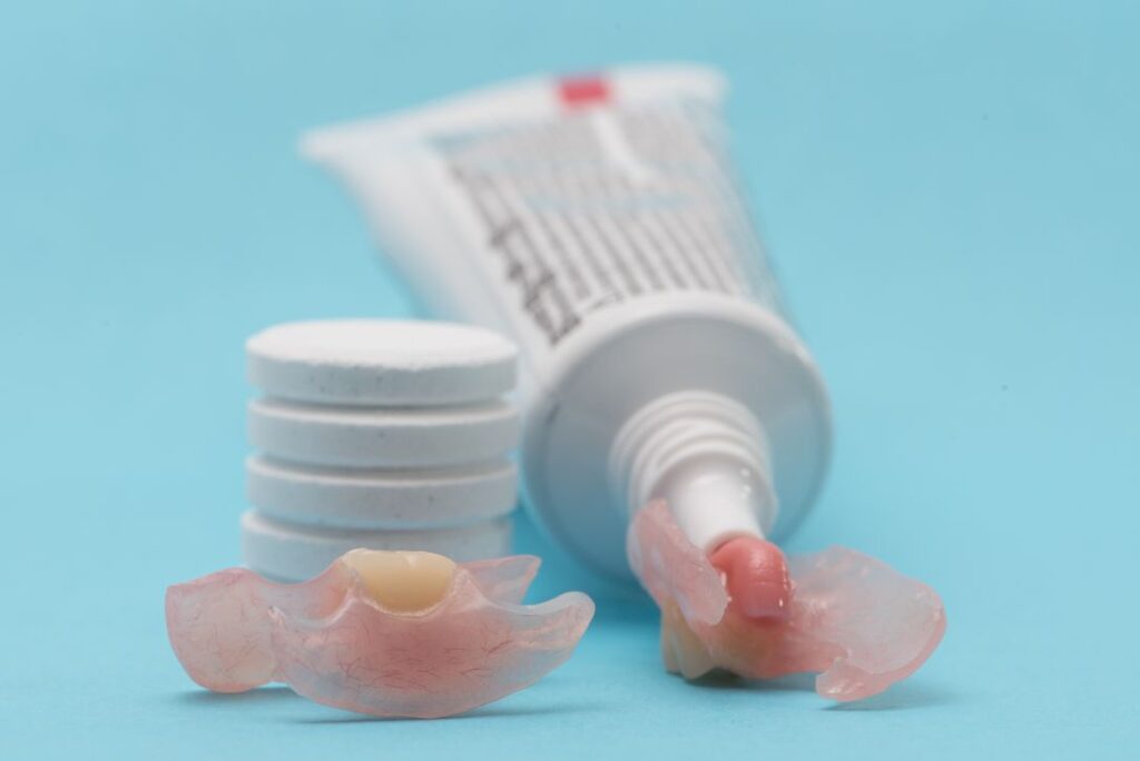 A denture and tube of denture adhesive